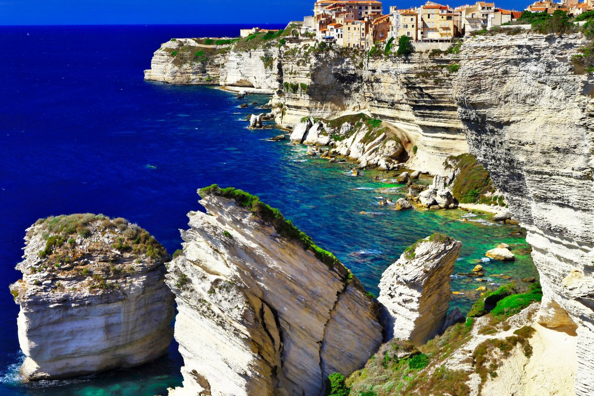 Bonifacio, Korsika – baltų kalkakmenio uolų miestas virš jūros, valtys prieplaukoje