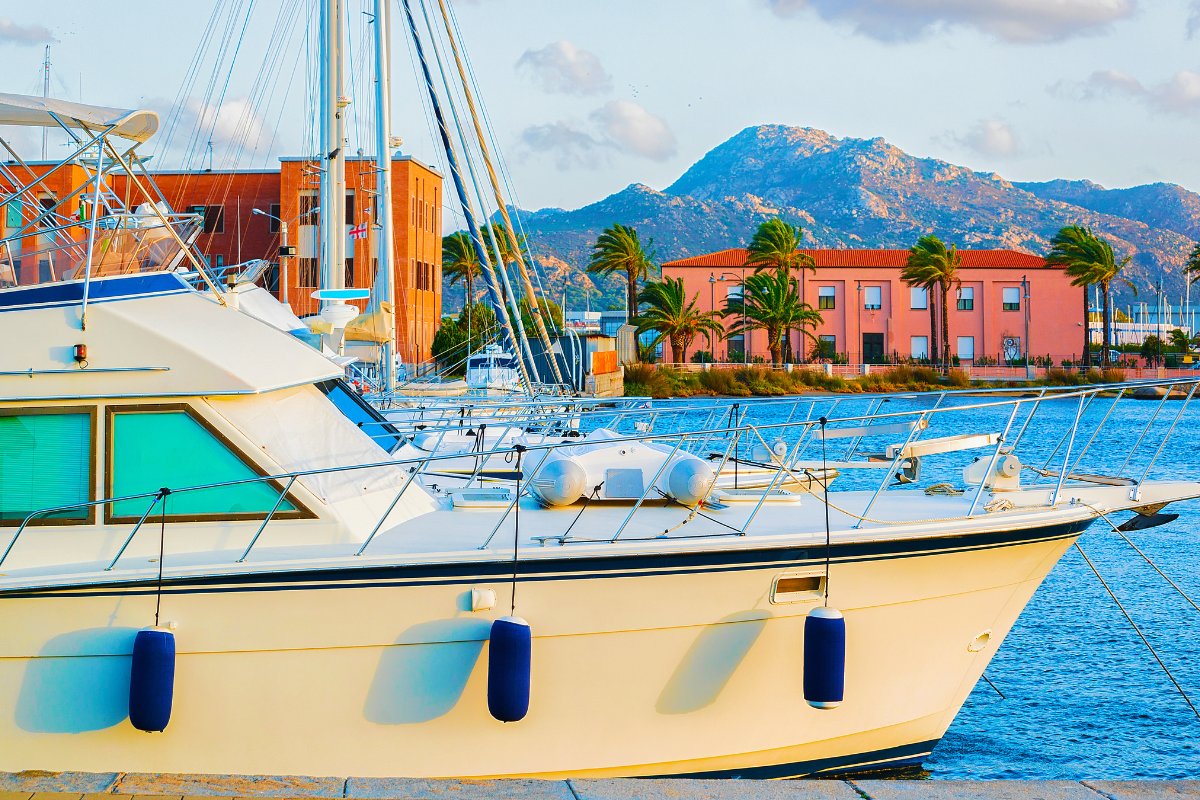 Olbia, Sardinija – bazinis uostas su laivais, miesto panorama fone